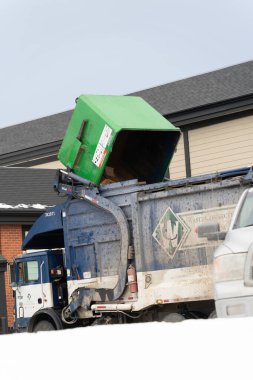 Çöp kamyonu, alışveriş merkezinin arkasındaki çöp kutusunu boşaltıyor.