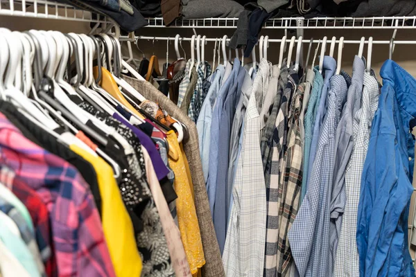 Мужская и женская одежда расставлены и висят в шкафу — стоковое фото