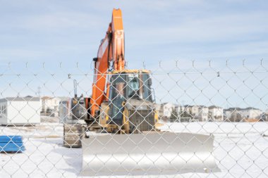 İnşaat ekipmanları tel örgülerin arkasında.