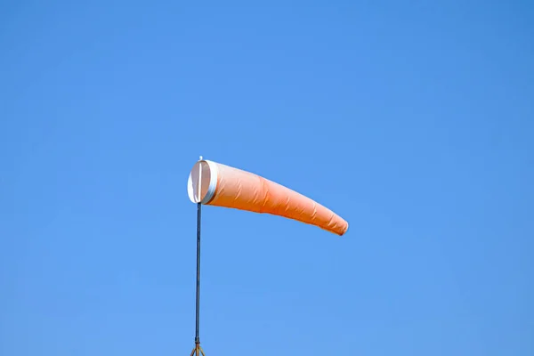 orange wind sock flying in the wind to show wind direction