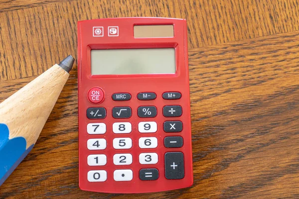 Riesiger Bleistift mit rotem Taschenrechner auf Bürotisch — Stockfoto