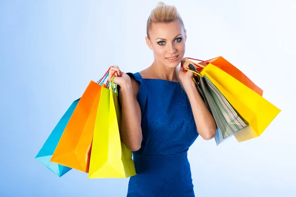 Happy blonde woman holding bunch of vibrant shopping bags after — Stock Photo, Image