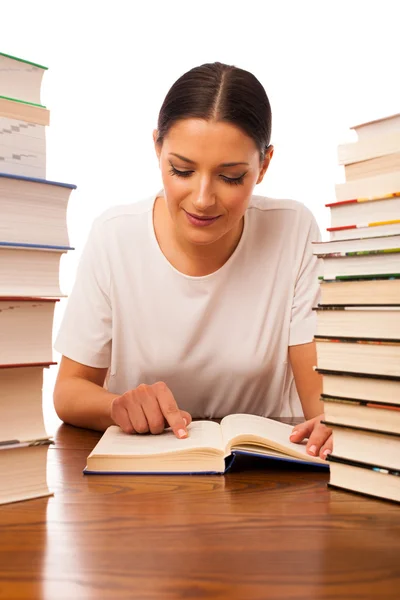 Excited woman reading behind the table between two pile of books — Stock Photo, Image