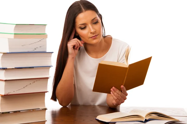 Excited woman concentrated reading behind the table with pile of — Stock Photo, Image