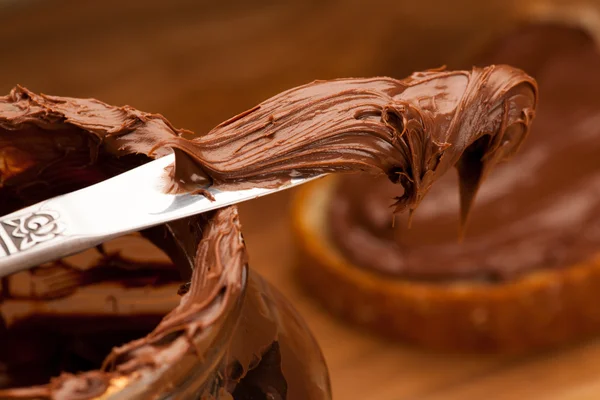 Bıçak cam kavanoz yayılan tatlı çikolata nuga dolu. — Stok fotoğraf