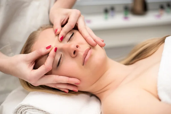 Mujer joven acostada en la mesa de masaje recibiendo masaje facial. Beaut. — Foto de Stock