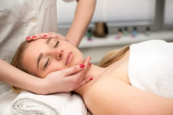 Jovem deitada na mesa de massagem recebendo massagem facial. Beaut... — Fotografia de Stock