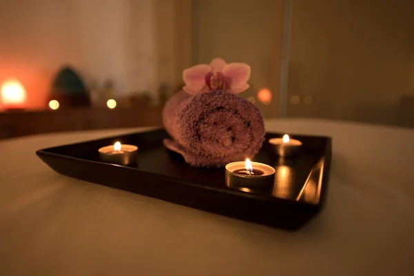 Оформление салона красоты в массажном кабинете, свечи, полотенце и орхидея — стоковое фото