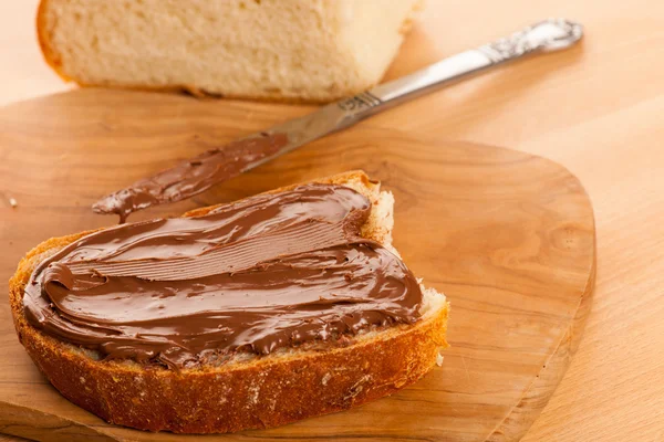 Fatia de pão com nougat de chocolate doce espalhada nas costas de madeira — Fotografia de Stock