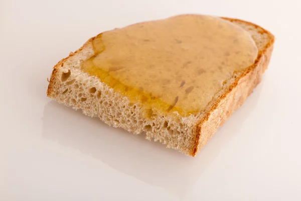 Doce mel dourado pegajoso em uma fatia de pão fresco . — Fotografia de Stock