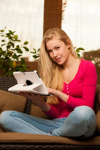 Woman comfortable sitting on sofa and using tablet computer. — Stock Photo, Image