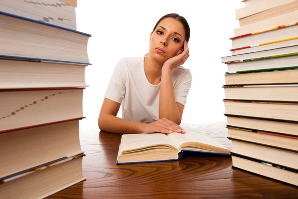 Sick and tired woman reading behind the table between two pile o — Stock Photo, Image