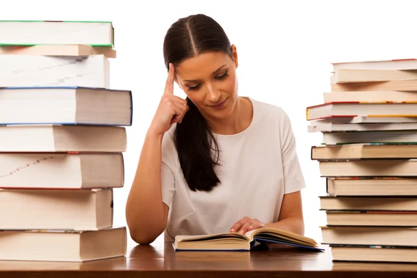 Vrouw achter de tafel tussen twee stapel boeken lezen. — Stockfoto