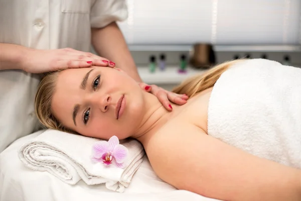 Mujer joven acostada en la mesa de masaje recibiendo masaje facial. Beaut. — Foto de Stock