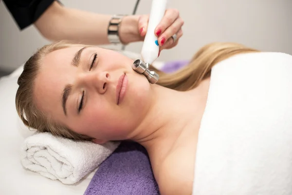 Mujer joven acostada en la mesa de masaje recibiendo masaje facial. Beaut. — Foto de Stock