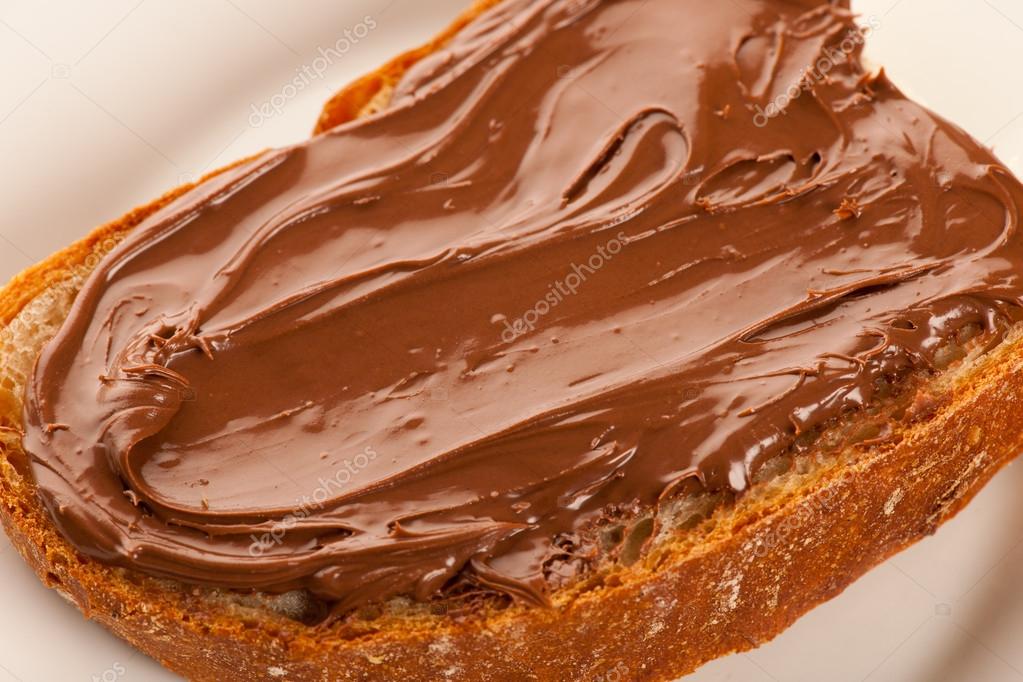 Dilim ekmek ve tatlı çikolata nuga ile beyaz tabakta yaymak Stok