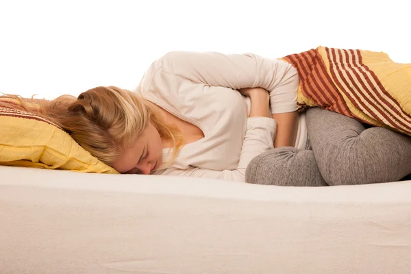 Mujer acostada en la cama sosteniendo el vientre debido al dolor de estómago . — Foto de Stock