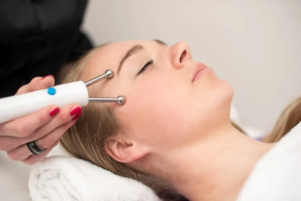 Mujer joven acostada en la mesa de masaje recibiendo masaje facial. Beaut. — Foto de Stock