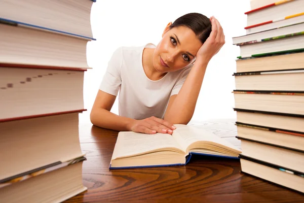 Sick and tired woman reading behind the table between two pile o — Stock Photo, Image