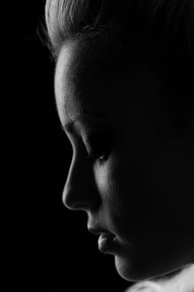 Vrouw staand silhuette in duisternis met zacht licht op gezicht. — Stockfoto