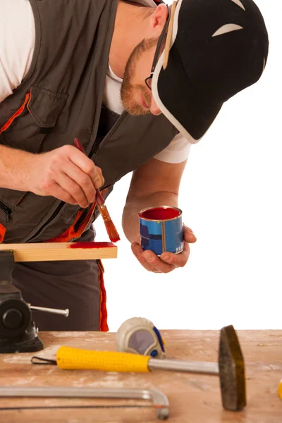 A carpenter pinting wood in red color isolated over white backgr Stock Picture