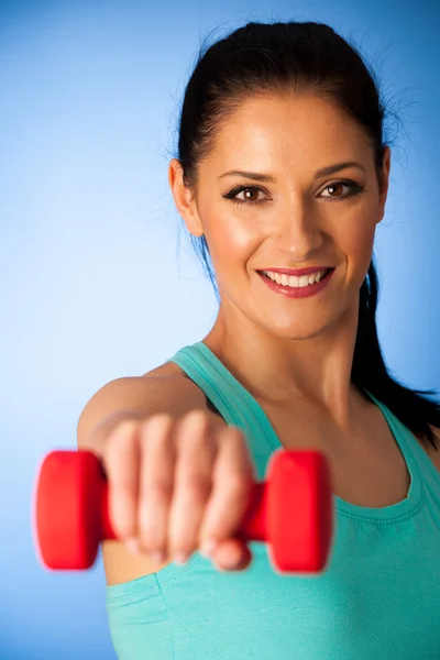Aktivní žena s činkami cvičení v posilovně fitness nad modrou bac — Stock fotografie