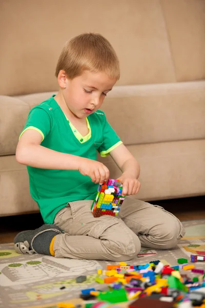 Młody chłopak gra z bloków na ziemi w pokoju dziennym — Zdjęcie stockowe