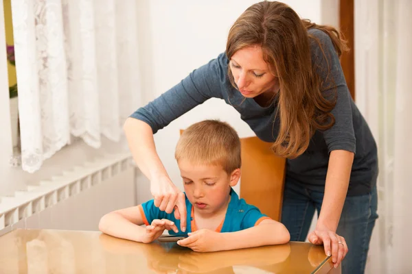 Madre e hijo juegan en el teléfono inteligente en la mesa — Foto de Stock