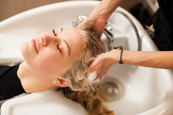 Cabeleireiro no trabalho - cabeleireiro lavando o cabelo ao cliente — Fotografia de Stock