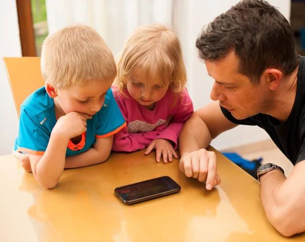 Padre hijo y niña revisando el teléfono inteligente — Foto de Stock