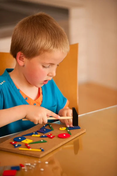 Niño jugando con bloques y clavos en una mesa en la cocina —  Fotos de Stock