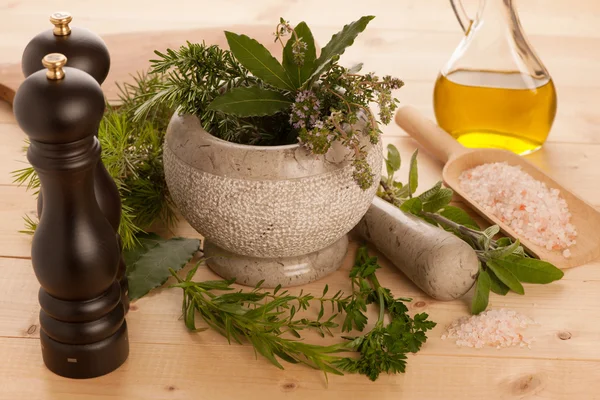 Diverse kruiden op een houten tafel met Mortier, de stamper en de molens. — Stockfoto