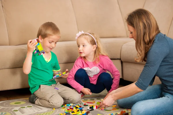 Kinder und ihre Mutter spielen mit Klötzen auf dem Boden — Stockfoto