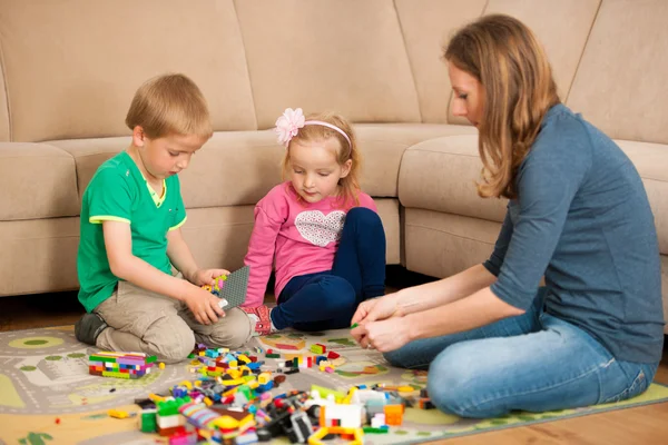 Crianças e sua mãe estão brincando com blocos no chão — Fotografia de Stock