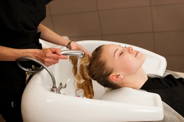 Cabeleireiro no trabalho - cabeleireiro lavando o cabelo ao cliente — Fotografia de Stock