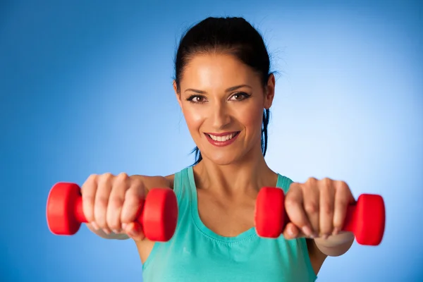 Mulher ativa com halteres treino na academia de fitness sobre bac azul — Fotografia de Stock