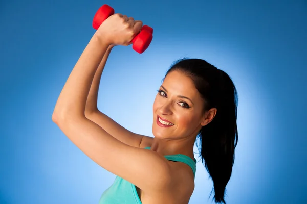 Aktive Frau mit Kurzhanteln trainiert im Fitnessstudio über blauem Bac — Stockfoto
