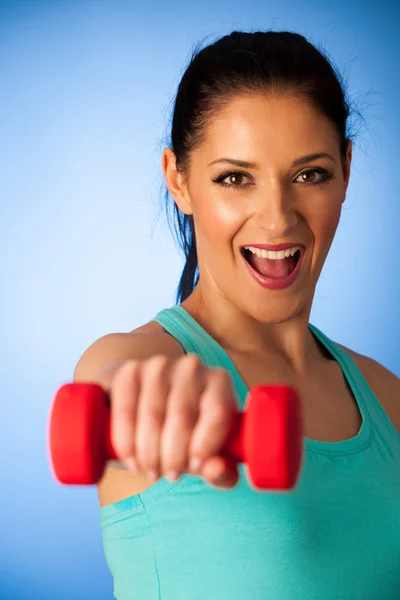 Mujer activa con pesas entrenamiento en gimnasio sobre bac azul — Foto de Stock