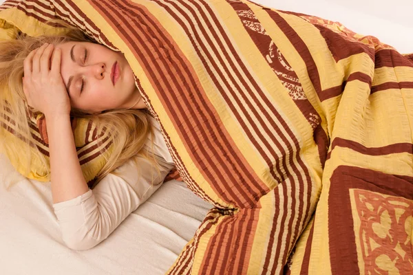 Больная женщина лежит в постели покрыты одеялом, чувствует себя плохо, имеет f — стоковое фото