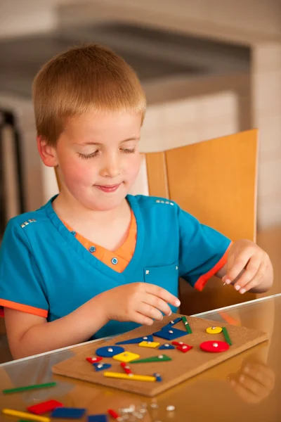 Boy playing with blocks and nails on a table in kitchen — Stock Photo, Image