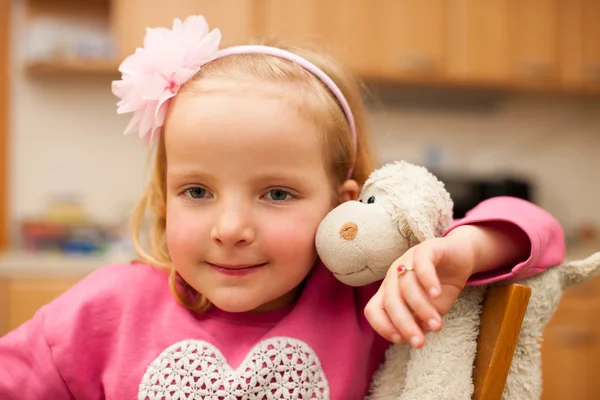 Cute little blonde girl plays with sheep toy in livingroom — Stock Photo, Image