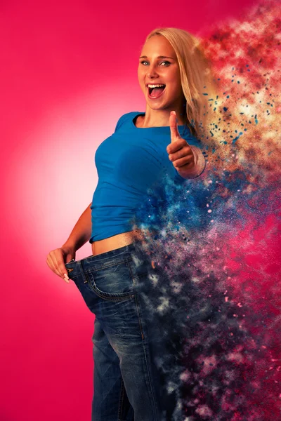 Estilo de vida saludable - mujer rubia en forma con un gesto pantalones demasiado grandes — Foto de Stock