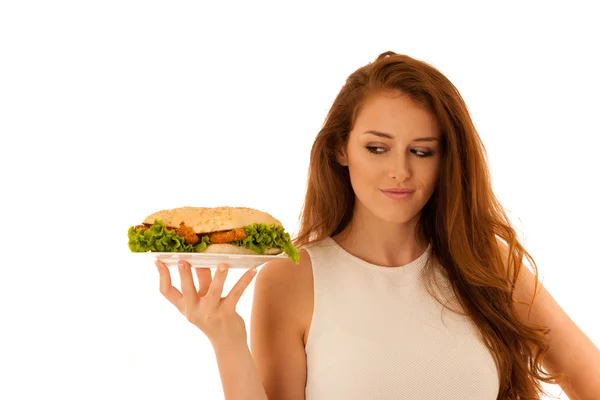 Ohälsosam måltid - glad ung kvinna äter hamburgare isolerade över — Stockfoto