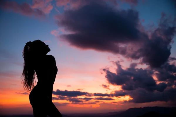 Kadın başarıyı işaret ediyor - akşam gökyüzünde siluet — Stok fotoğraf