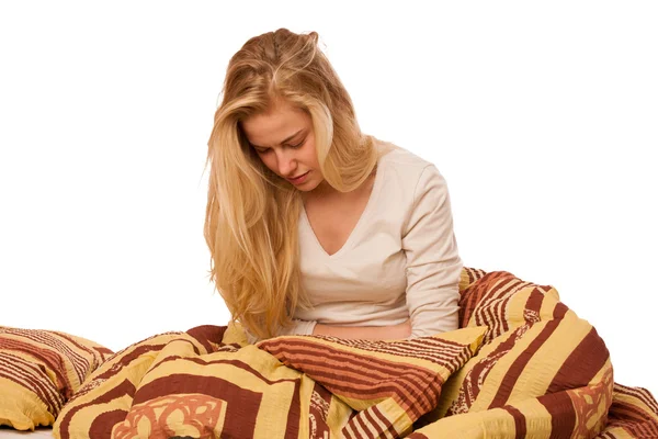 Woman sitting on bed holding belly because of the pain in stomac — Stock Photo, Image