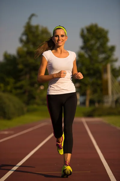 Preety young woman running on a track — Stock Photo, Image