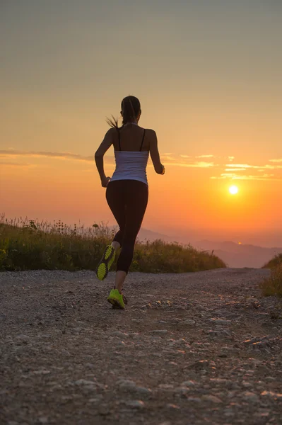 Frau läuft bei Sonnenuntergang auf einer Bergstraße — Stockfoto