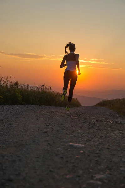 Mujer corriendo en un camino de montaña al atardecer de verano —  Fotos de Stock