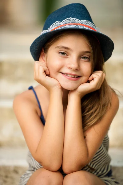 Cute young girl with hat sitting on stairs in park — Stock Photo, Image