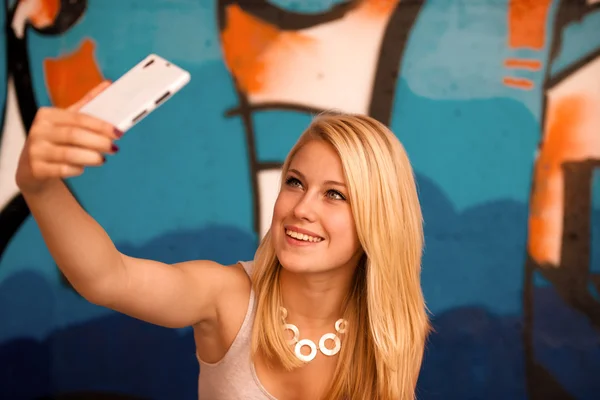 Vacker ung kvinna att göra en selfie utomhus nära graffiti wal — Stockfoto